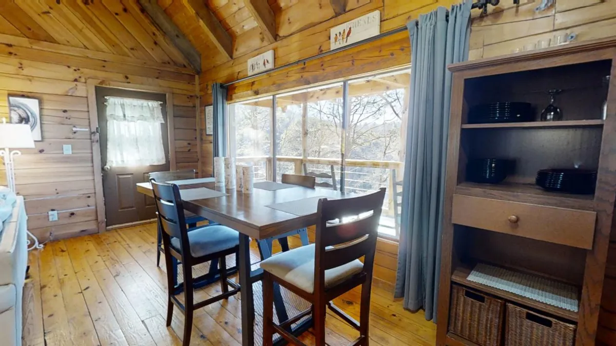 A spacious dining table set near large windows, surrounded by warm wooden cabinetry. The area invites shared meals, lively conversations, and scenic views, enhancing the sense of togetherness.